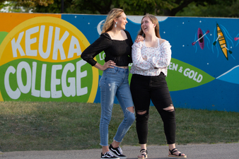 Sarah Tower '22 and Sydnie Brown '22 posing in front of the mural they designed and painted by Lightner Library